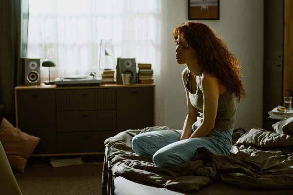 Mujer pensativa sentada al borde de la cama, reflejo del insomnio relacionado con la ansiedad