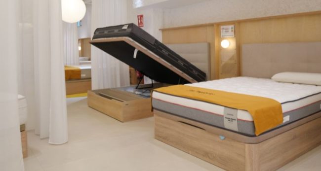 Canapé abatible abierto con colchón Flex y colchón Ingravity Termalfresh sobre canapé cerrado en tienda Colchón Exprés Ribera de Curtidores. Imagen con la frase '¿Duermes o descansas?'